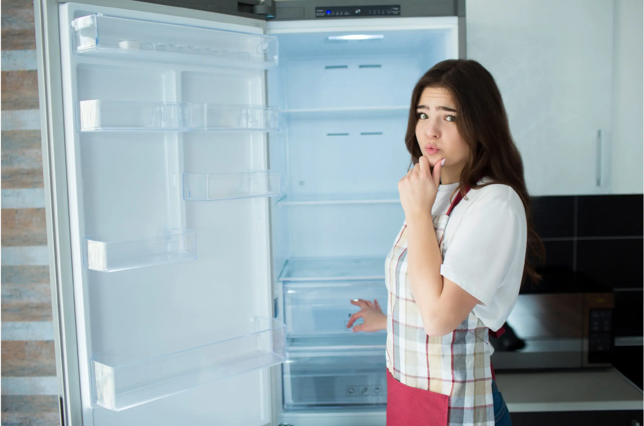 vrouw staat voor een lege open koelkast