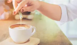 vrouw doet sucralose in de cappuccino