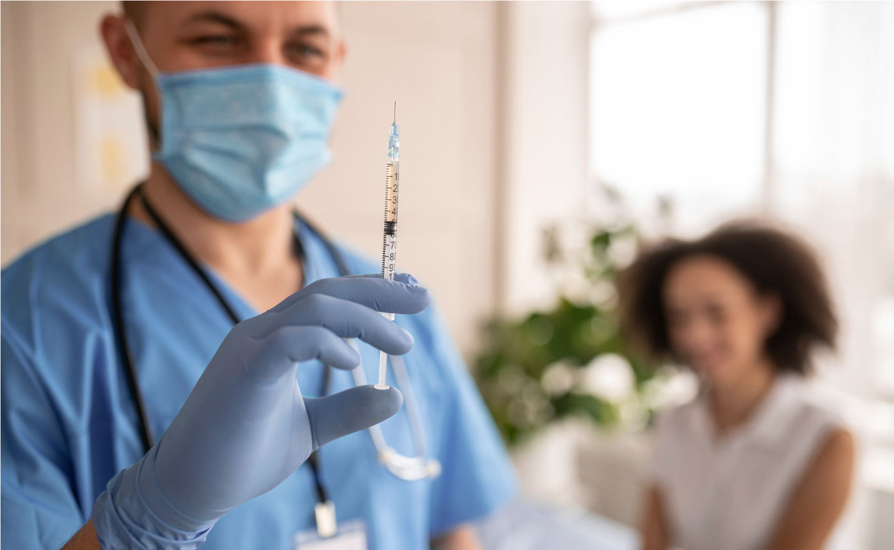 dokter houdt injectie vast naast vrouwelijke patient