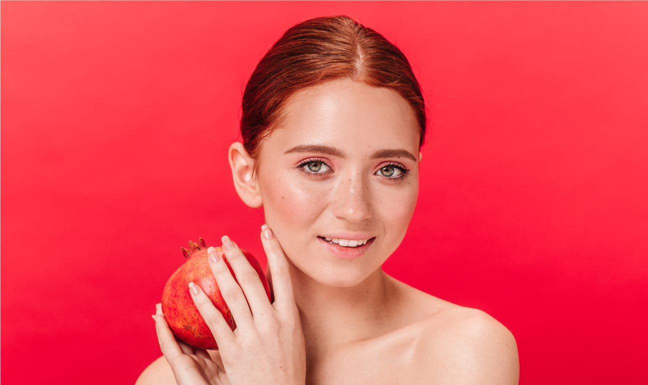 vrouw houdt granaatappel naast gezicht