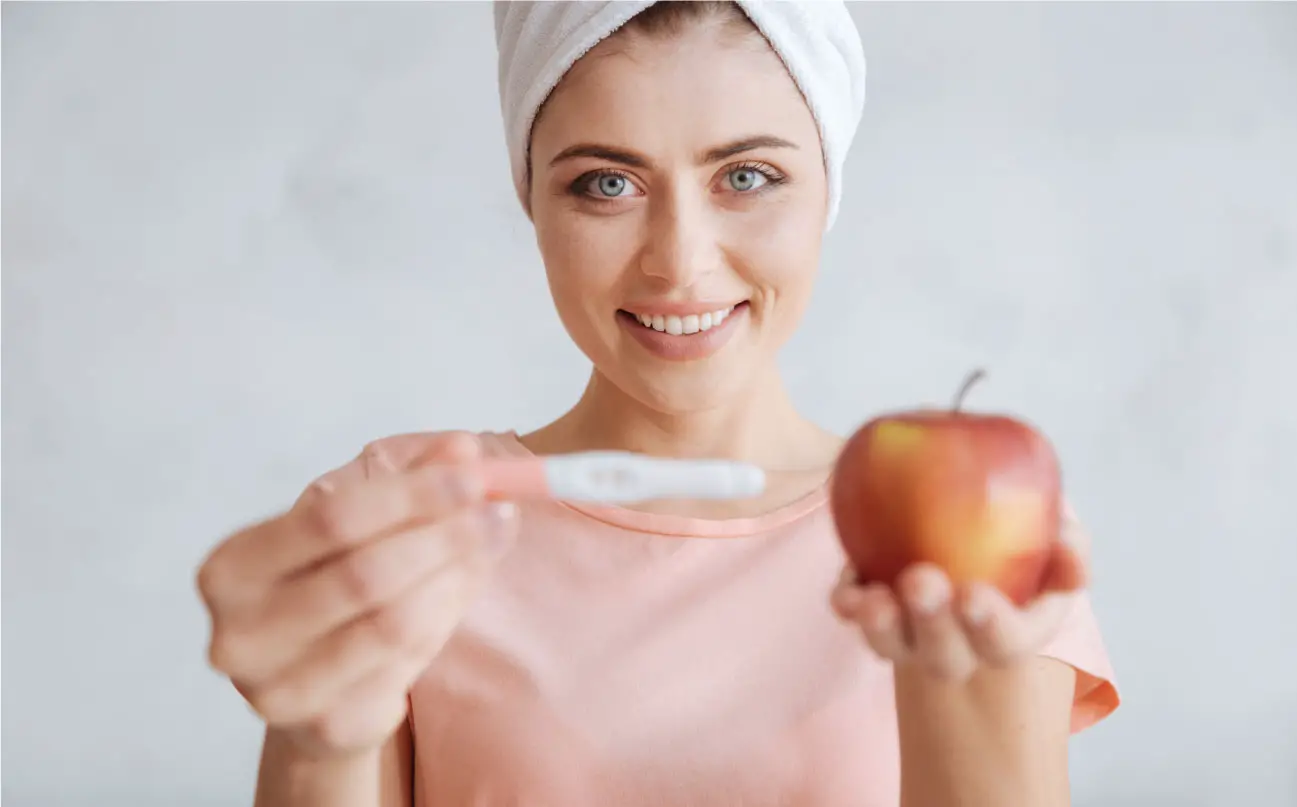 vrouw met vruchtbaarheidstest en appel in de hand