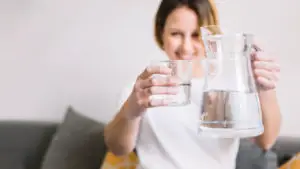 vrouw met kan en glas water in hand