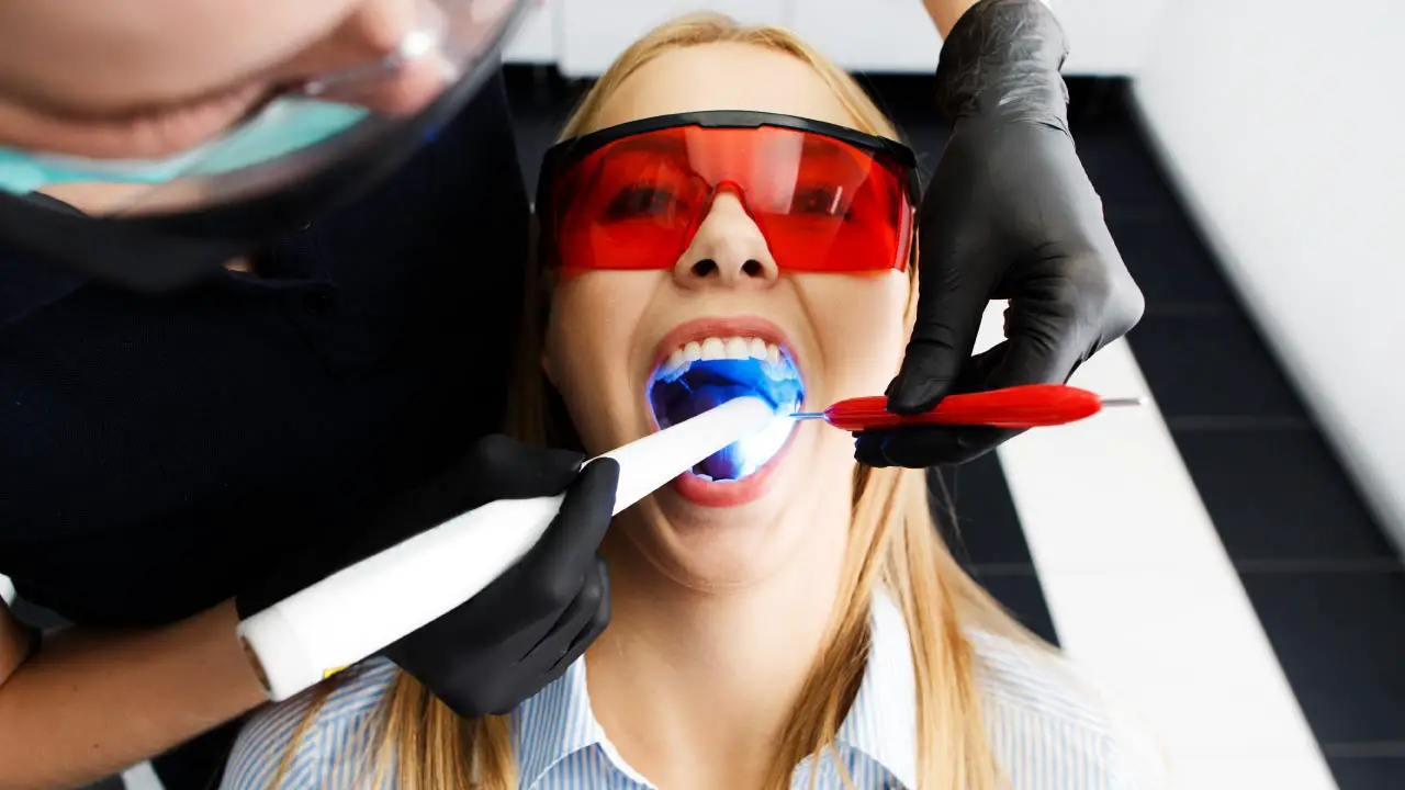 vrouw bleekt tanden bij tandarts