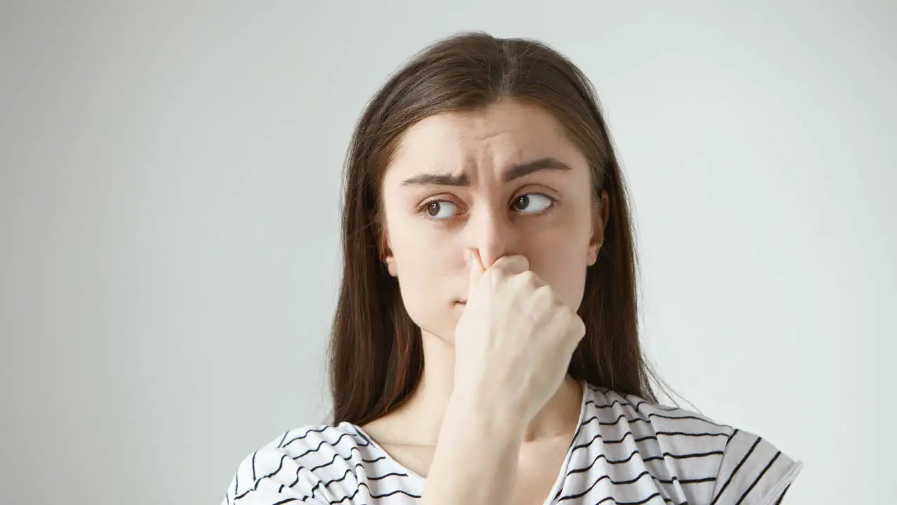 jonge vrouw knijpt neus dicht door stank