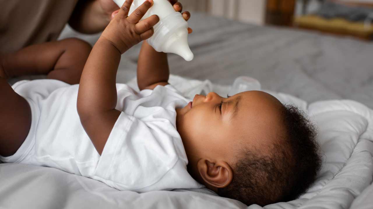 baby houdt een flesje melk vast