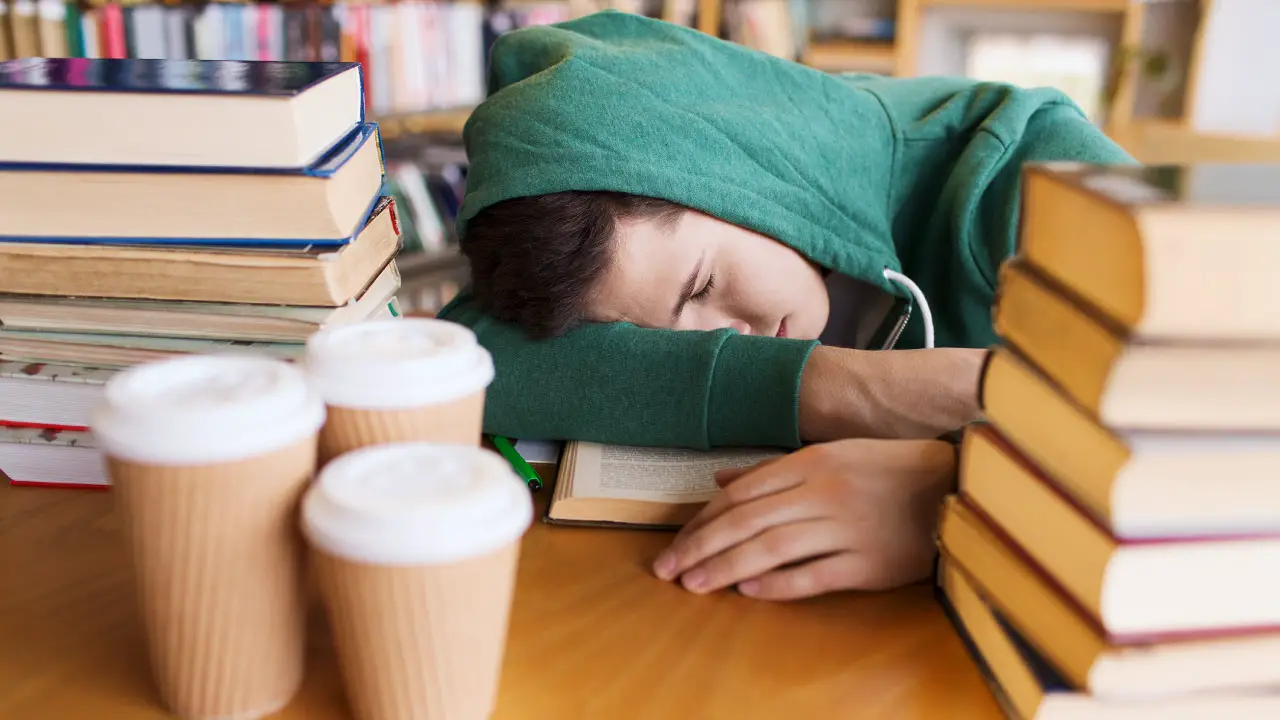 student-slaapt-op-boek-in-de-bibliotheek