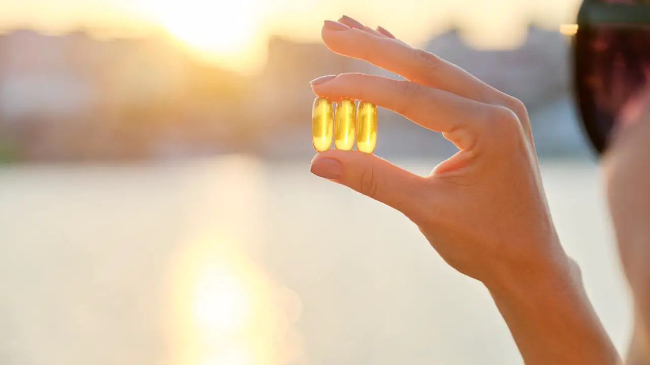 vrouw-houdt-gele-vitaminecapsules-voor-de-zon