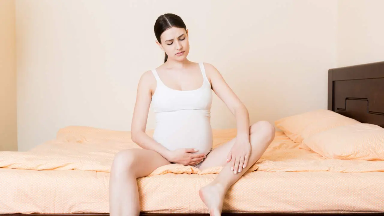 zwangere vrouw met kramp op bed