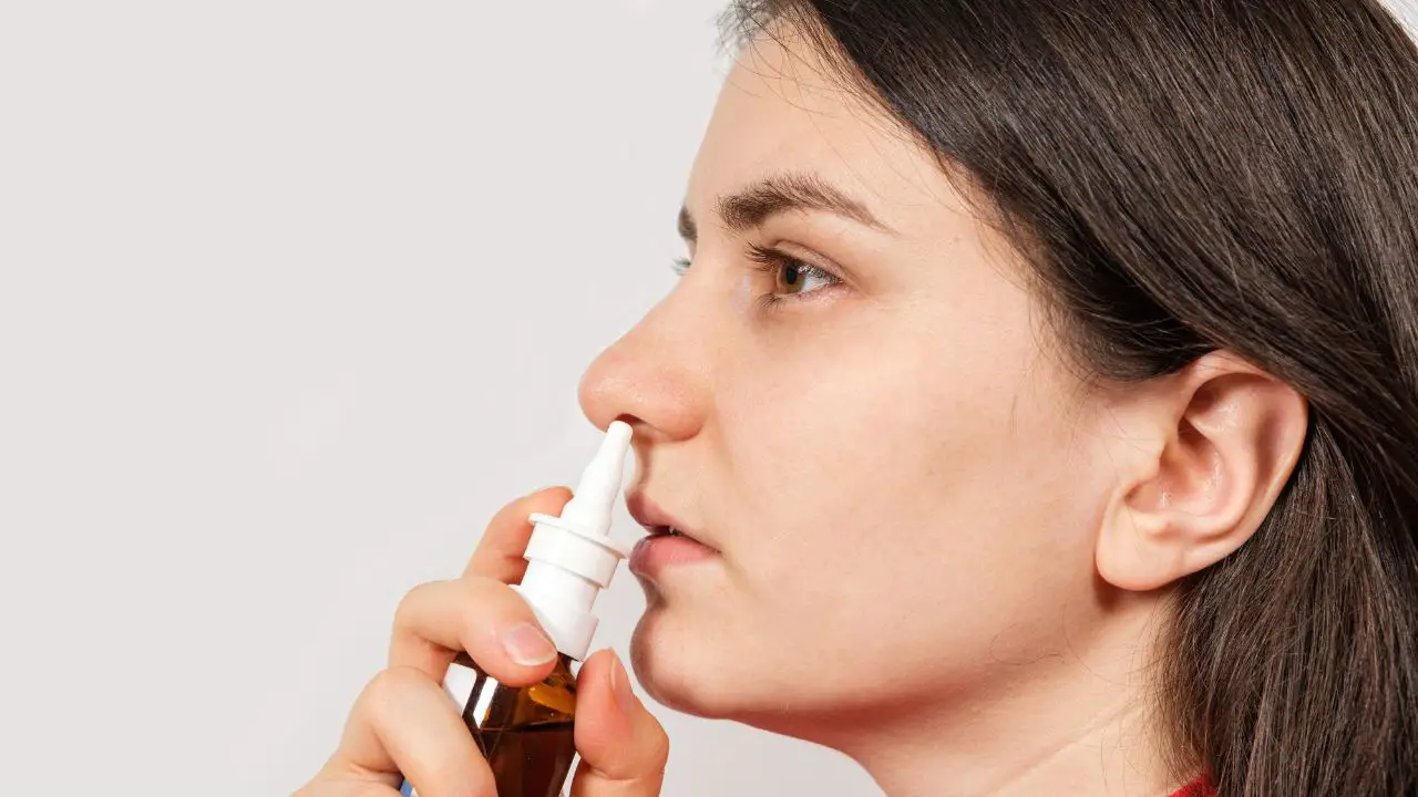 volwassen vrouw doet neusspray in linker neusgat