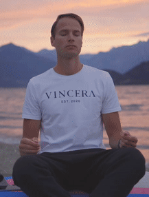 zittende man doet de vuurademhaling met zonsopkomst bij het como meer, draagt een wit vincera shirt
