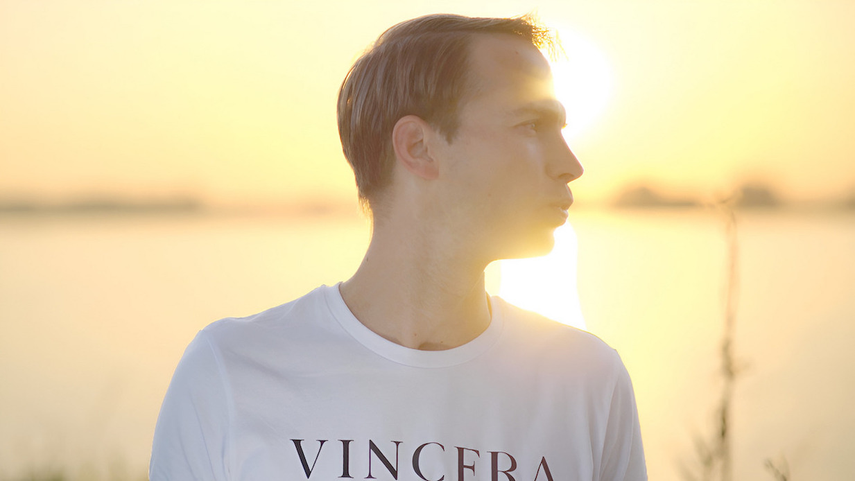 jonge man doet getuite lippen ademhaling tijdens de zonsopkomst, draagt een wit vincera shirt