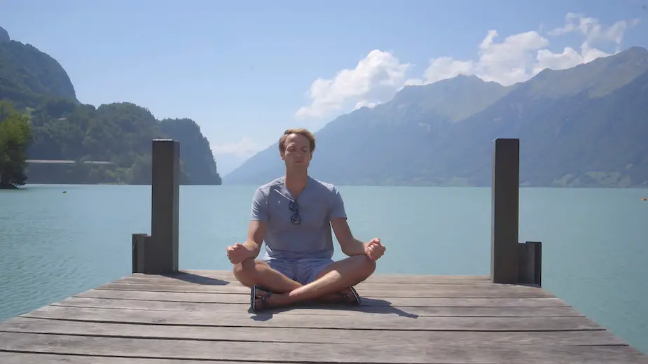zittende man bij een meer doet mindfulness ademhaling