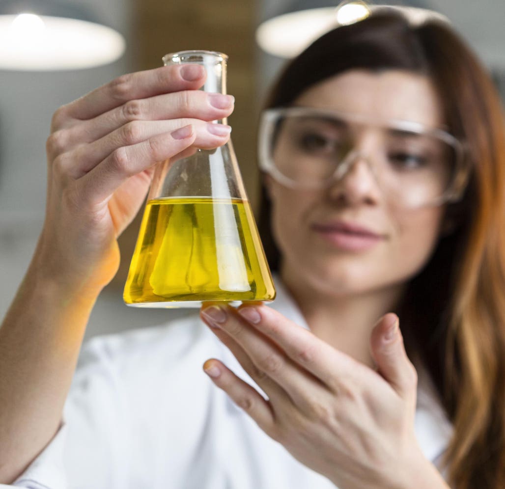 vrouwelijke wetenschapper met bril houdt glas vast met olijfolie daarin