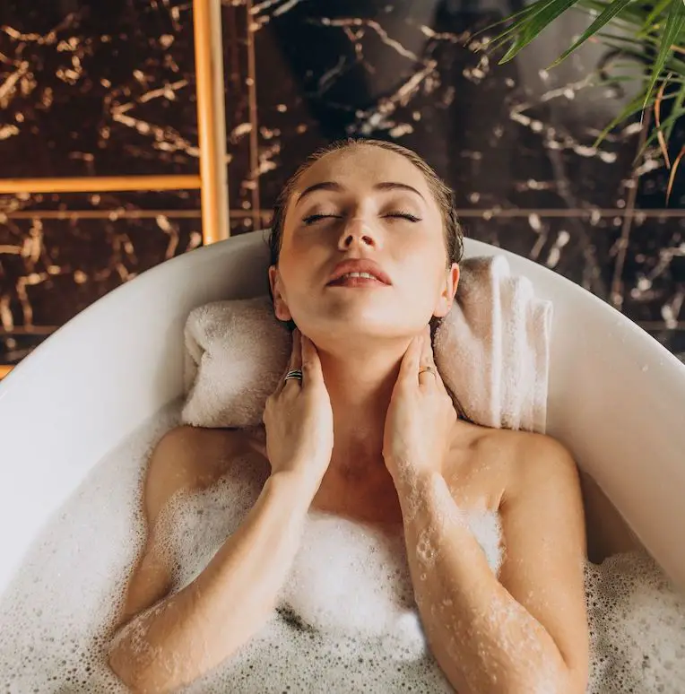 jonge vrouw ligt in bad met schuim