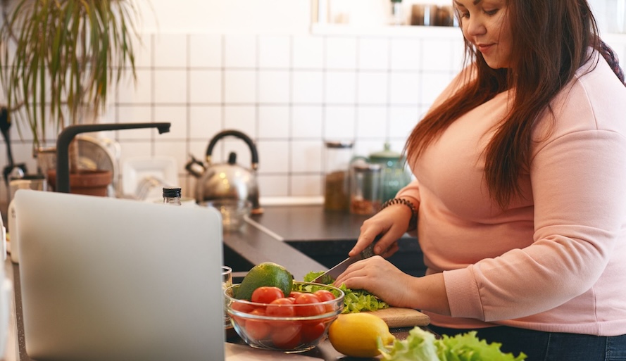 vrouw met overgewicht maakt in de keuken gezond eten klaar