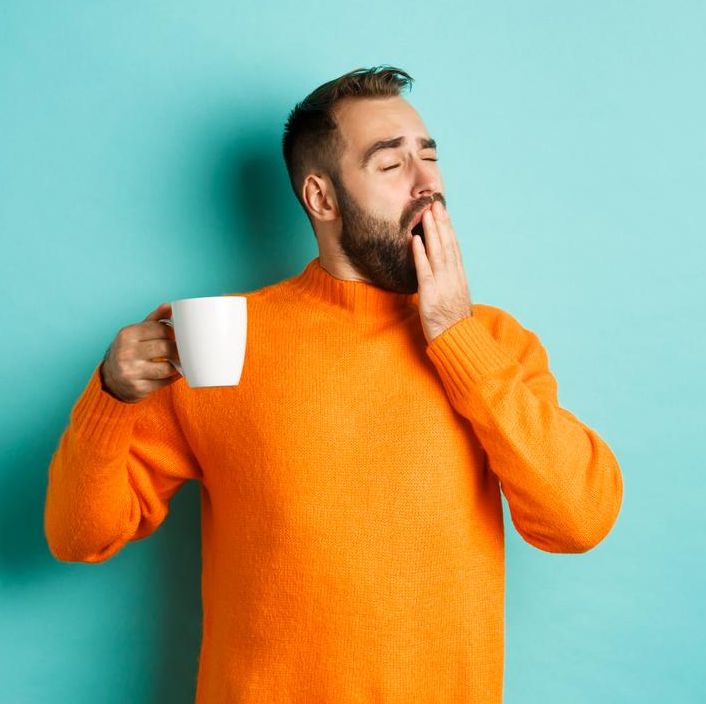 gapende man met een beker koffie in zijn hand