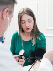 mannelijke dokter meet bloeddruk bij jonge vrouw