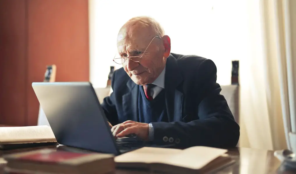 oude man werkt achter zijn bureau op een laptop